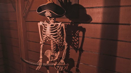 Menschliches Skelett mit Piratenhut und Säbel.