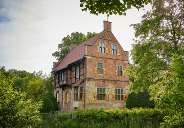 Das Haus Bisping, ein altes Fachwerkhaus, umgeben von Bäumen und Sträuchern.