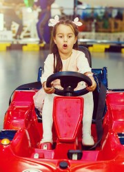 Ein Mädchen fährt Autoscooter in einem roten Auto.