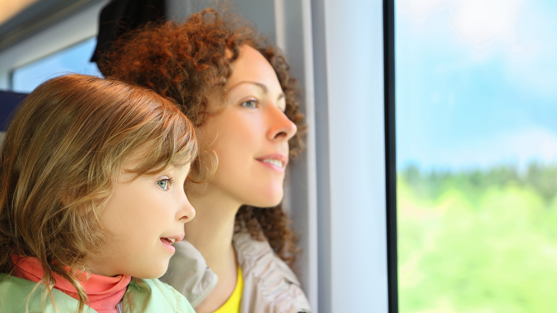 Mutter und Tochter schauen im Zug aus dem Fenster.