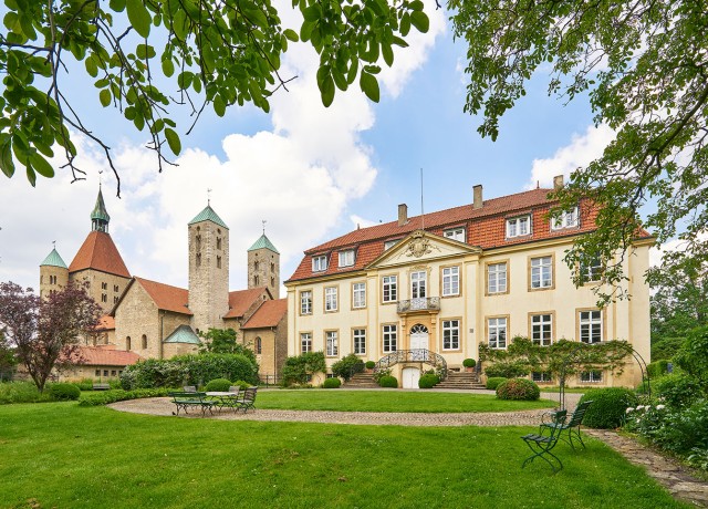 Schloss Freckenhorst mit weitläufigem Garten. Links daneben eine Kirche mit vier Türmen.